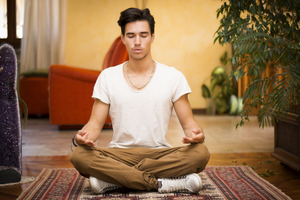 Young man meditating on the floor of his living room