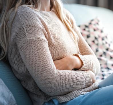 girl sitting on couch holding stomach