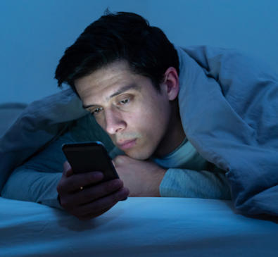Man reading phone at night in bed