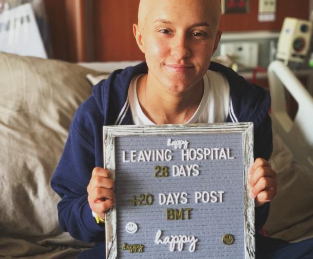 Cancer patient holding message board on discharge day from hospital