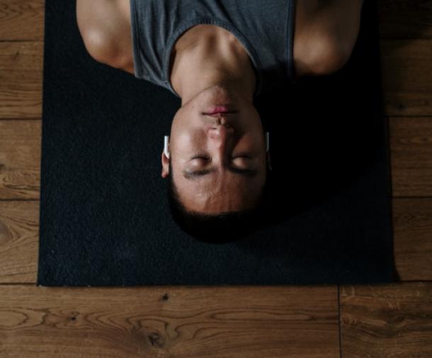 man laying with eyes closed on yoga mat