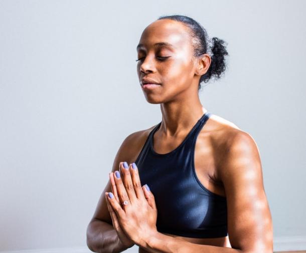 woman seated on yoga mat with hands together