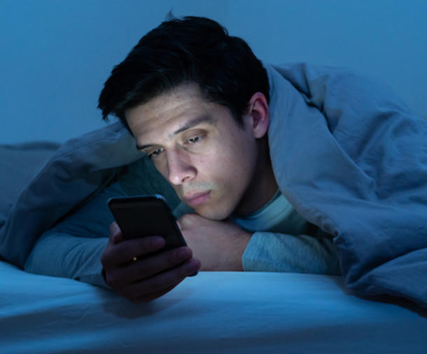 Man reading phone at night in bed