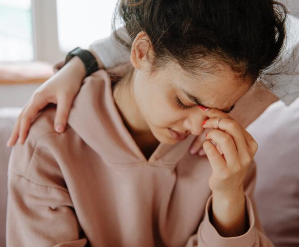 Young woman crying with hands on her shoulders